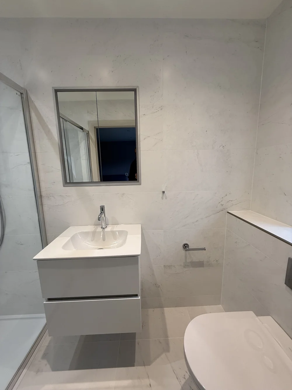 Compact marble ensuite with wall-hung vanity and back-to-wall WC — Haslemere bathroom fitters