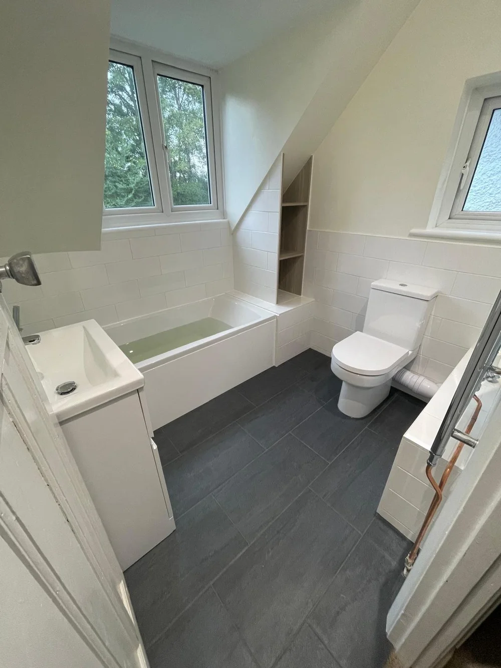 Bright loft family bathroom with metro tiles and slate-tiled floor — bathroom installation Haslemere