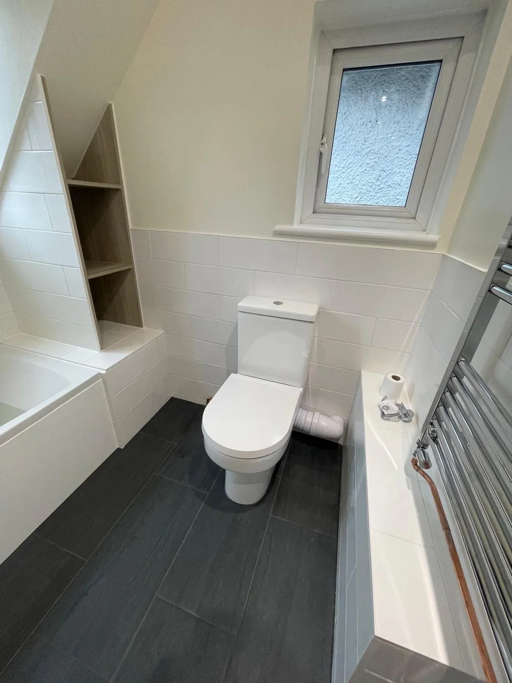 Loft bathroom with metro tiles, bespoke oak shelving and slate floor — bathroom installers Haslemere