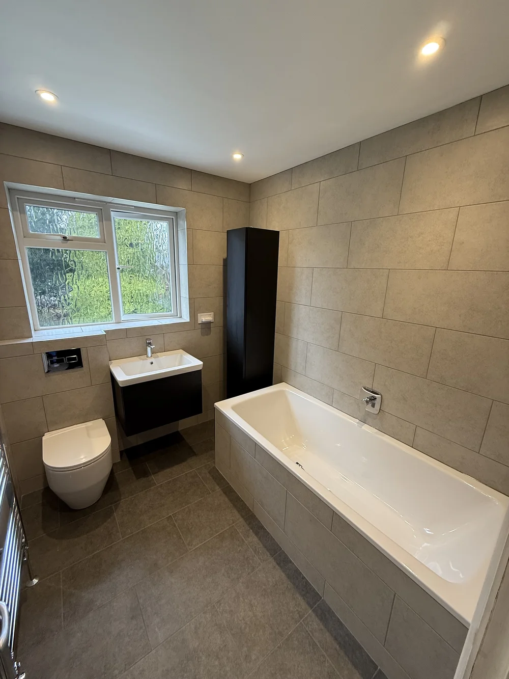 Fitted family bathroom with black vanity, tall storage and built-in bath — bathroom installers Haslemere