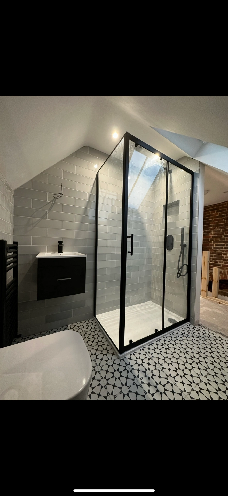 Loft ensuite with matte-black framed shower enclosure and patterned floor — Haslemere
