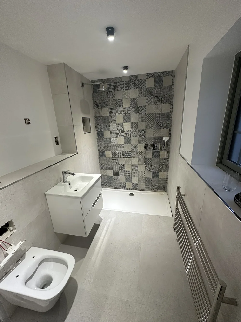 Modern shower room with patchwork feature tiles, white vanity and heated ladder rail — bathroom renovation Haslemere