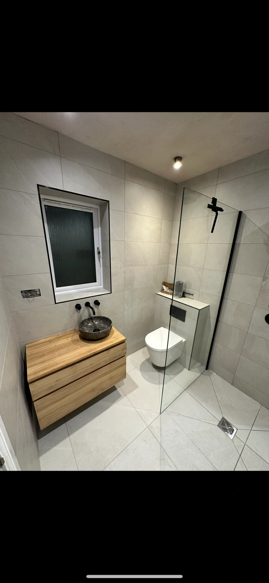 Wet room with oak floating vanity, stone vessel basin and black-framed walk-in shower — wet room installation Haslemere
