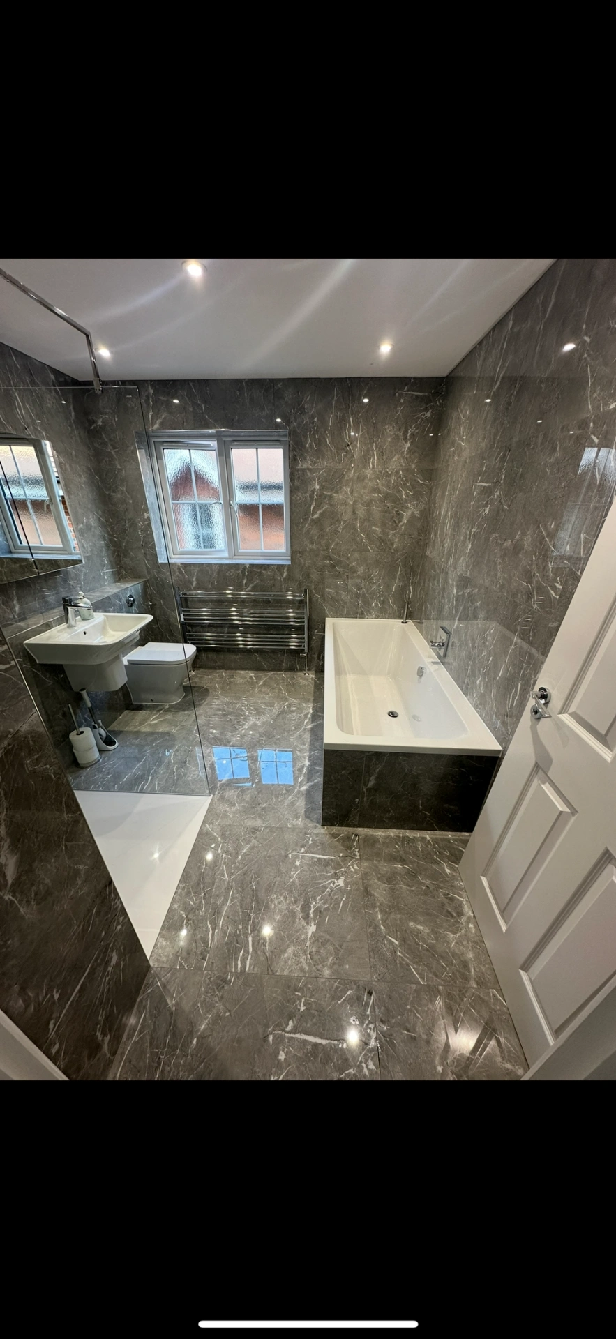 Grey marble family bathroom with double-ended bath and chrome towel rail — Haslemere
