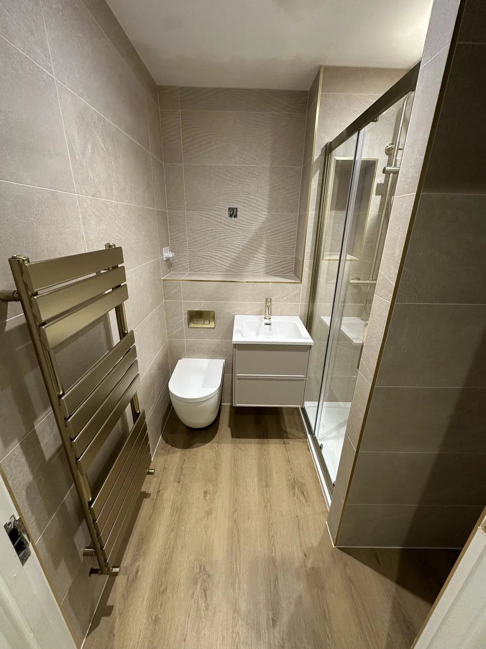 Modern shower room with brushed brass trim, sliding glass door and designer radiator — Haslemere bathroom fitters