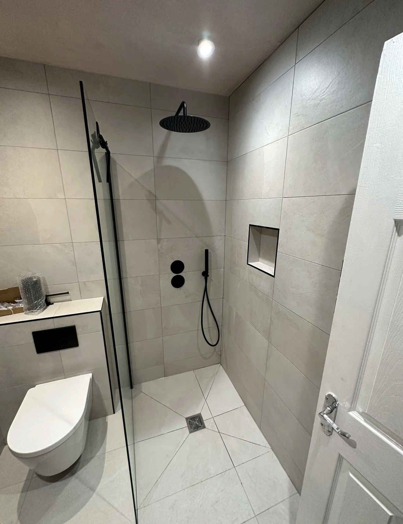 Minimal wet room with black rainfall shower and wall-hung WC — wet room installation Haslemere