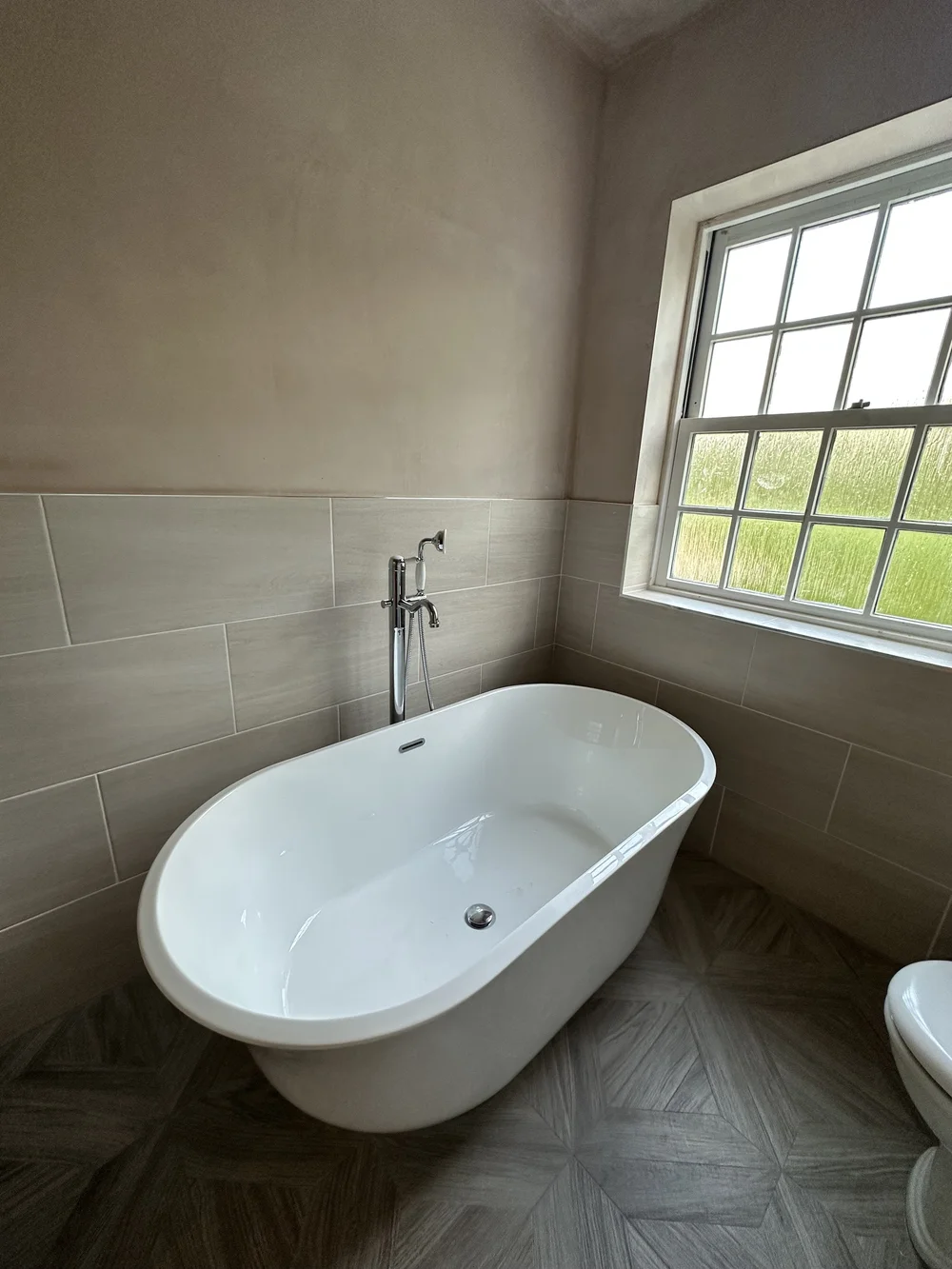 Traditional freestanding double-ended bath with chrome floor-mounted mixer and parquet floor — bathroom installation Haslemere