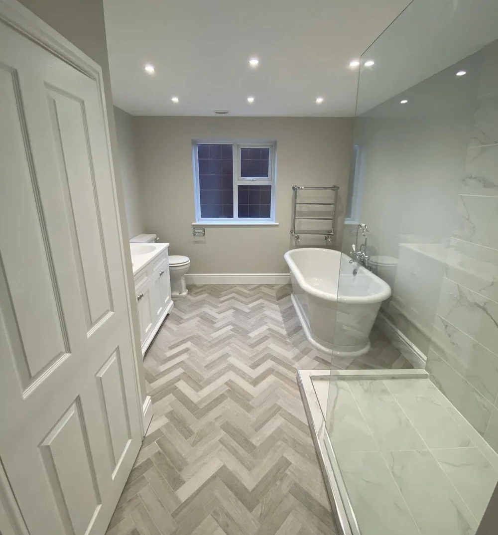 Traditional family bathroom with freestanding roll-top bath, herringbone floor and marble walk-in shower — bathroom installation Haslemere