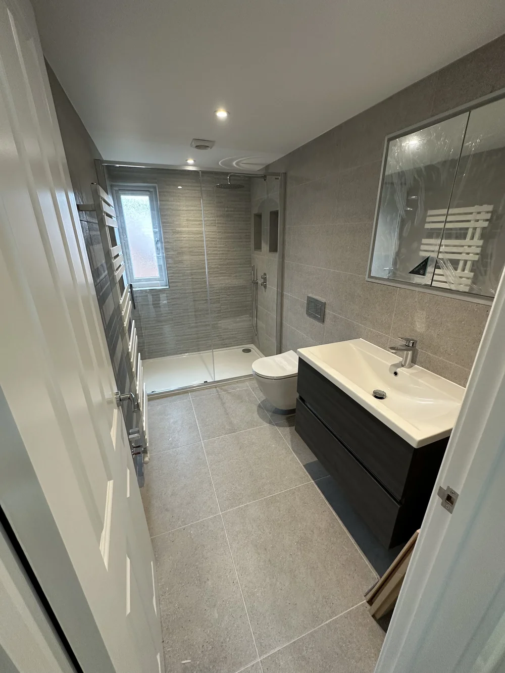 Grey stone-tiled shower room with graphite vanity and glass shower enclosure — bathroom installation Haslemere