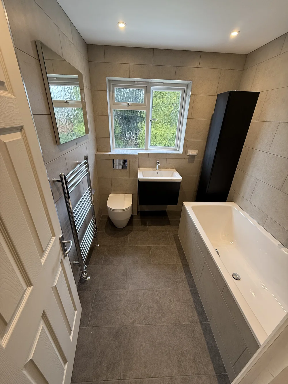 Compact family bathroom with black vanity, wall-hung WC and built-in bath — bathroom installation Haslemere