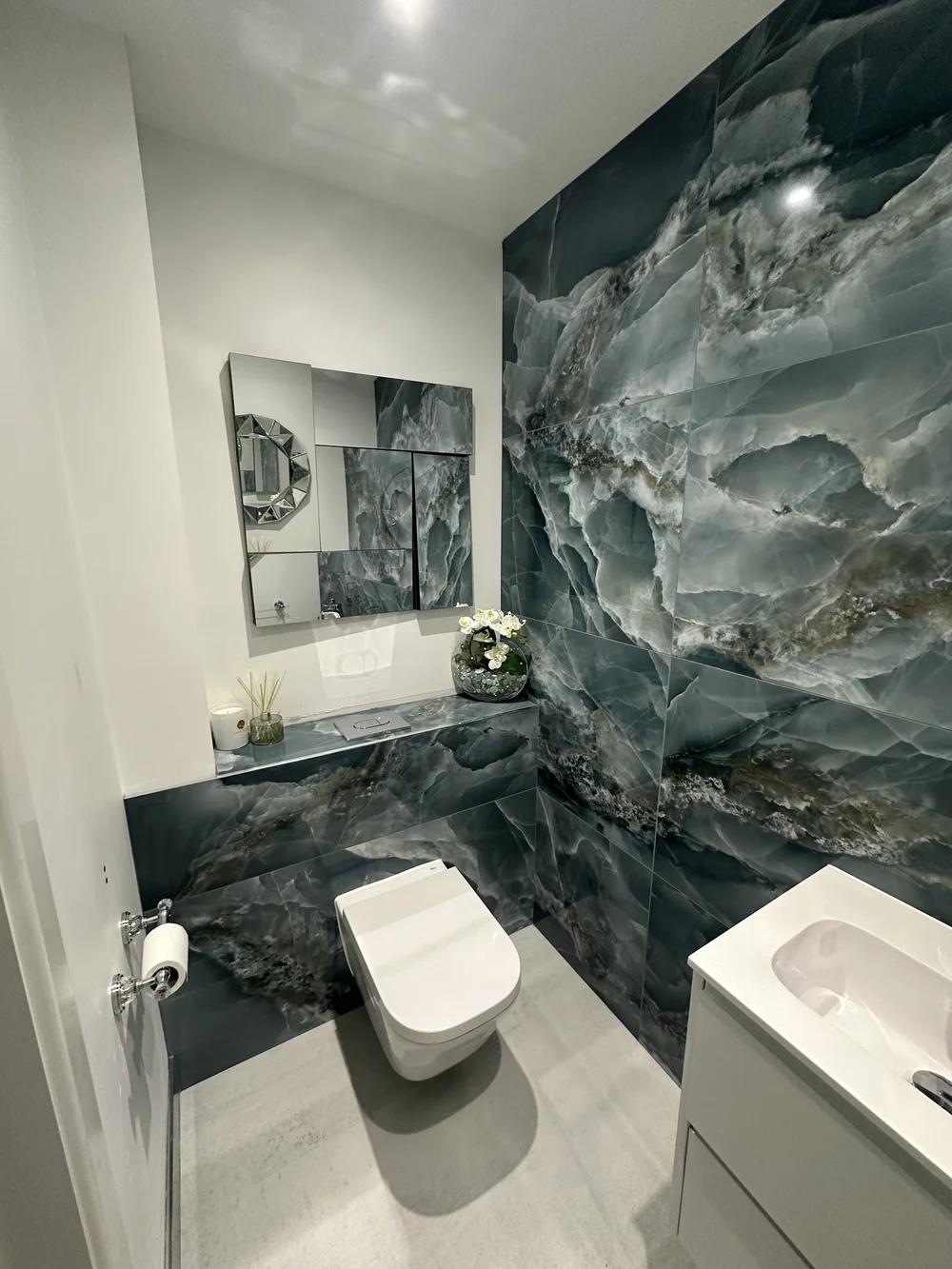 Bespoke cloakroom with full-height blue onyx feature wall and faceted mirror — bathroom design Haslemere