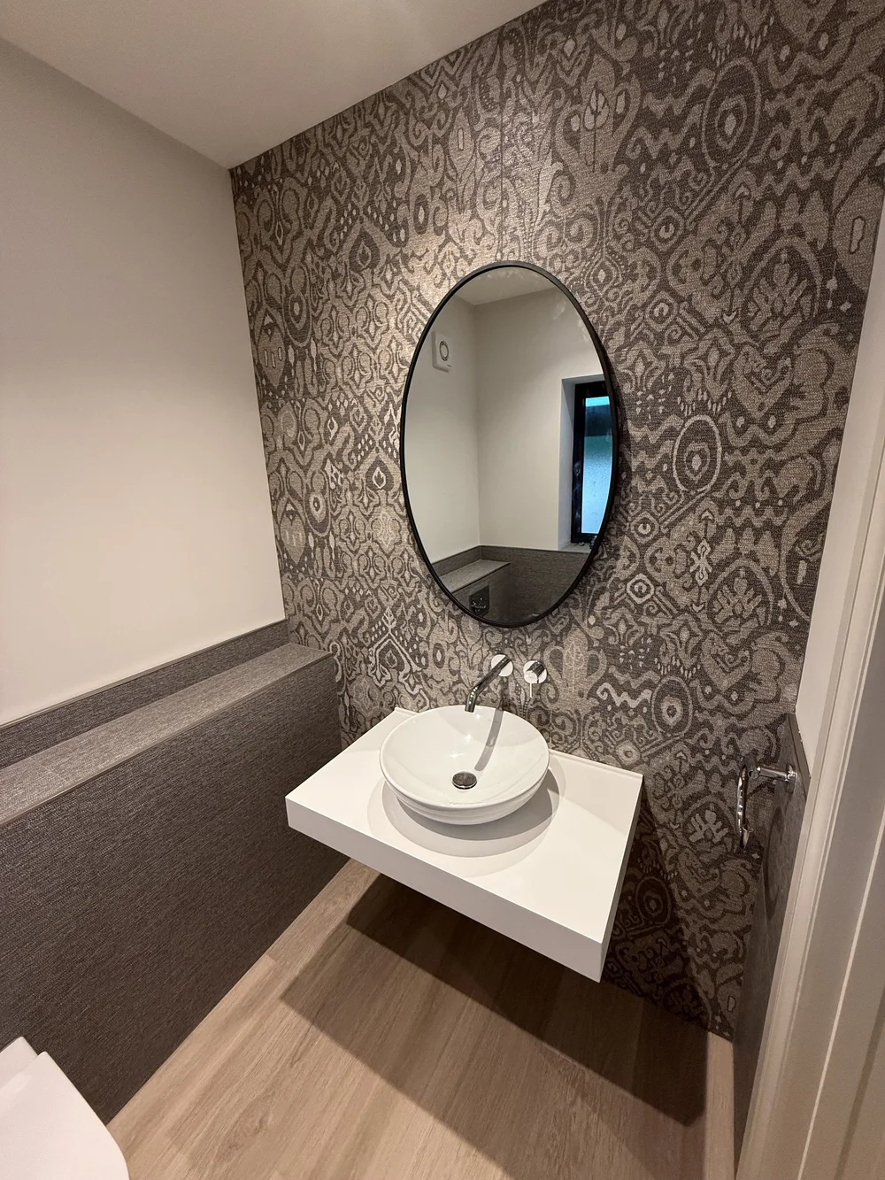 Feature-wall cloakroom with round black mirror and vessel basin — bathroom design Haslemere