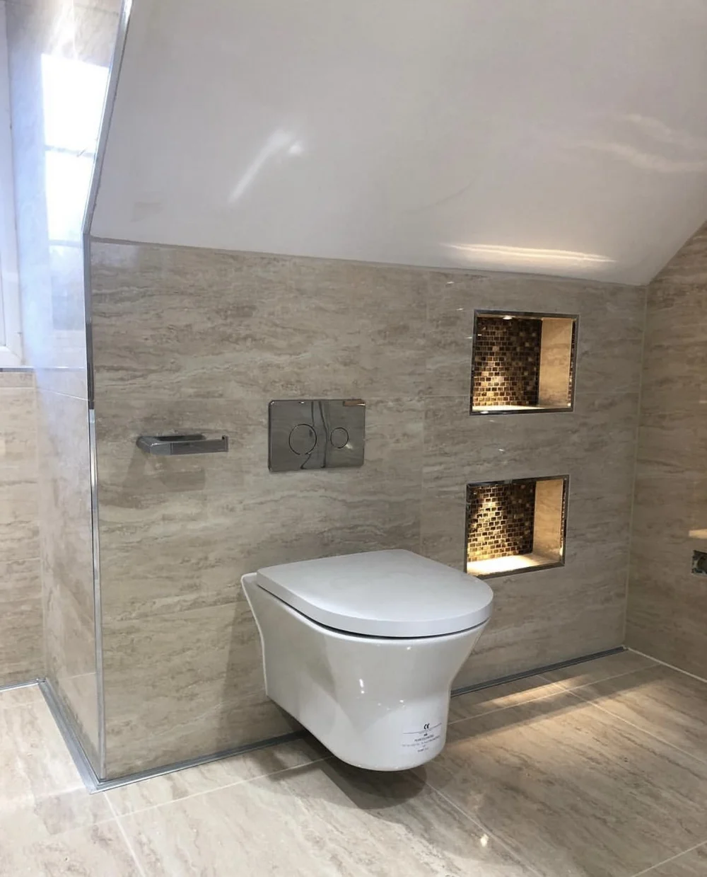 Travertine wet room with wall-hung WC and illuminated mosaic niches — bathroom renovation Haslemere