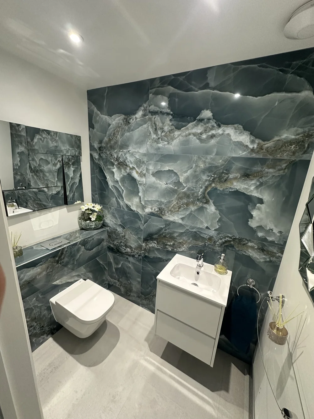 Cloakroom with blue onyx feature wall, wall-hung WC and floating white vanity — bathroom design Haslemere
