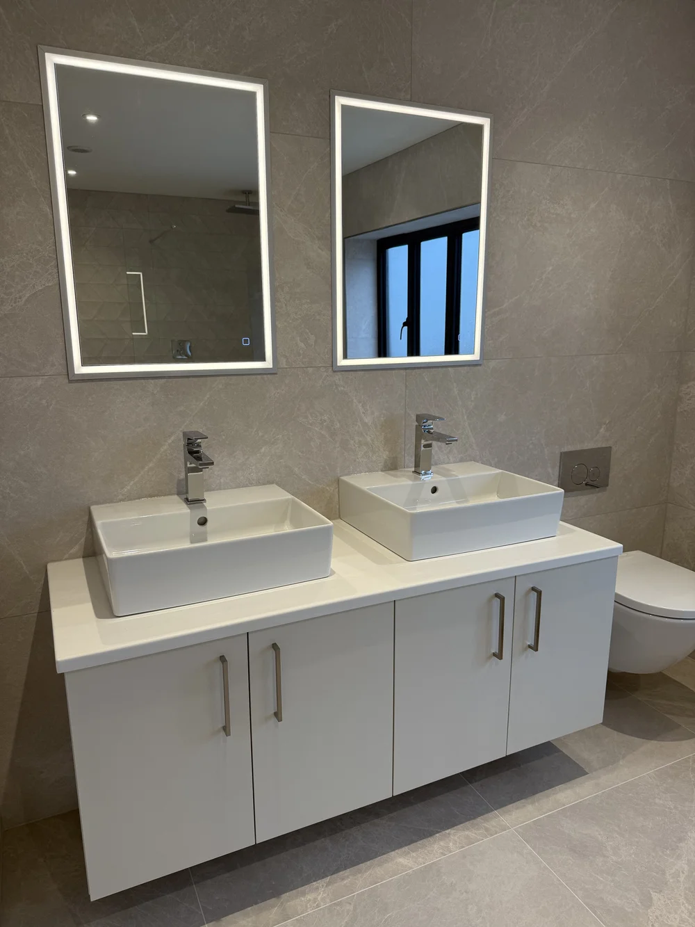 Twin countertop basins with LED mirrors on wall-hung vanity — ensuite installation Haslemere