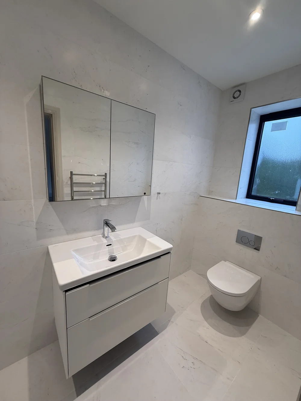 White marble family bathroom with wall-hung vanity and concealed cistern — Haslemere