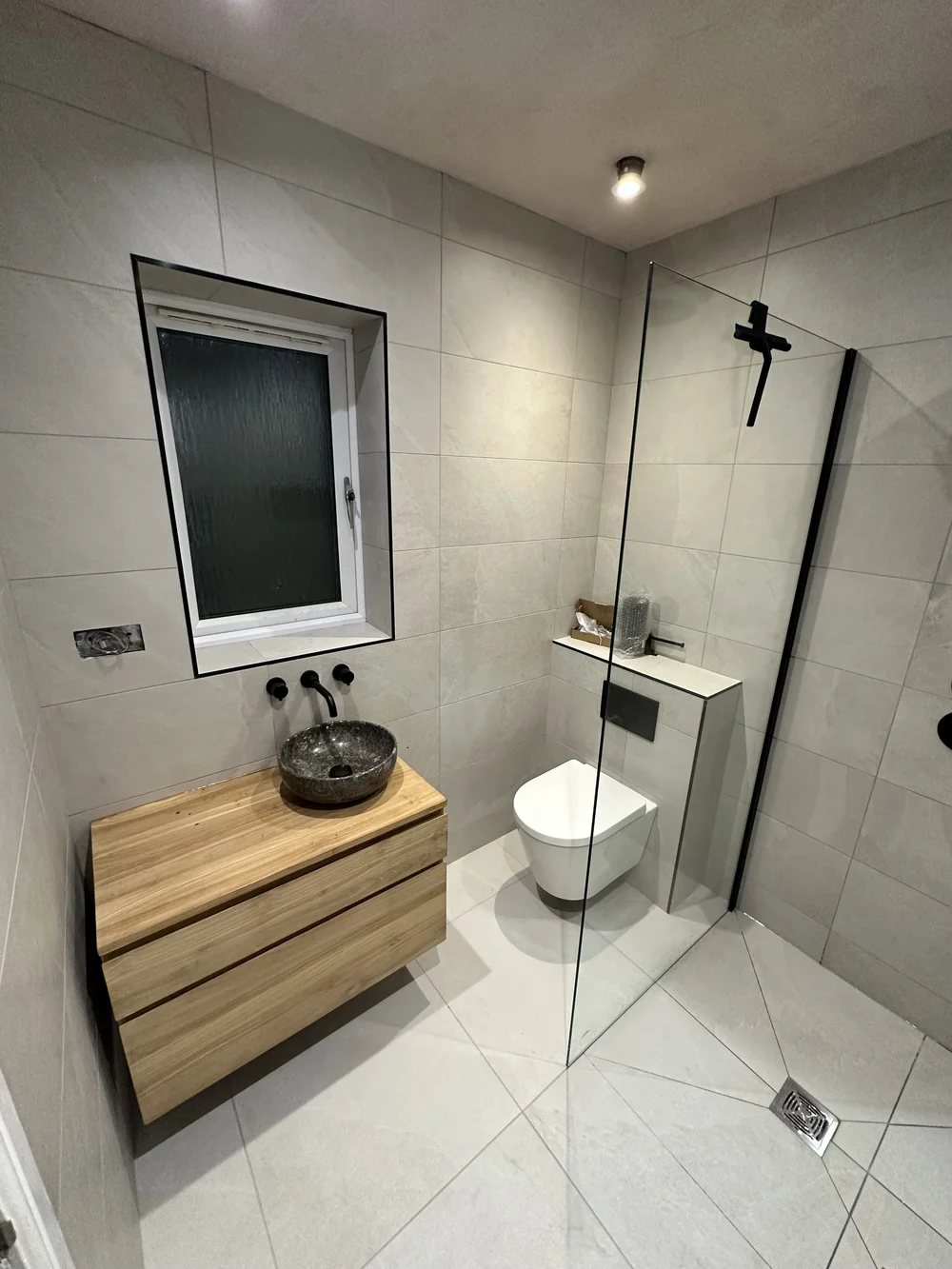 Wet room with oak floating vanity, stone basin and glass walk-in screen — wet room installation Haslemere