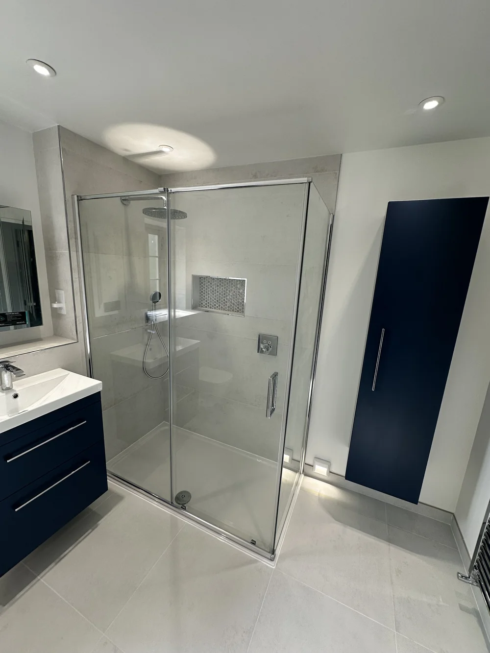 Contemporary shower room with navy wall cabinet, floating vanity and walk-in shower — bathroom installation Haslemere