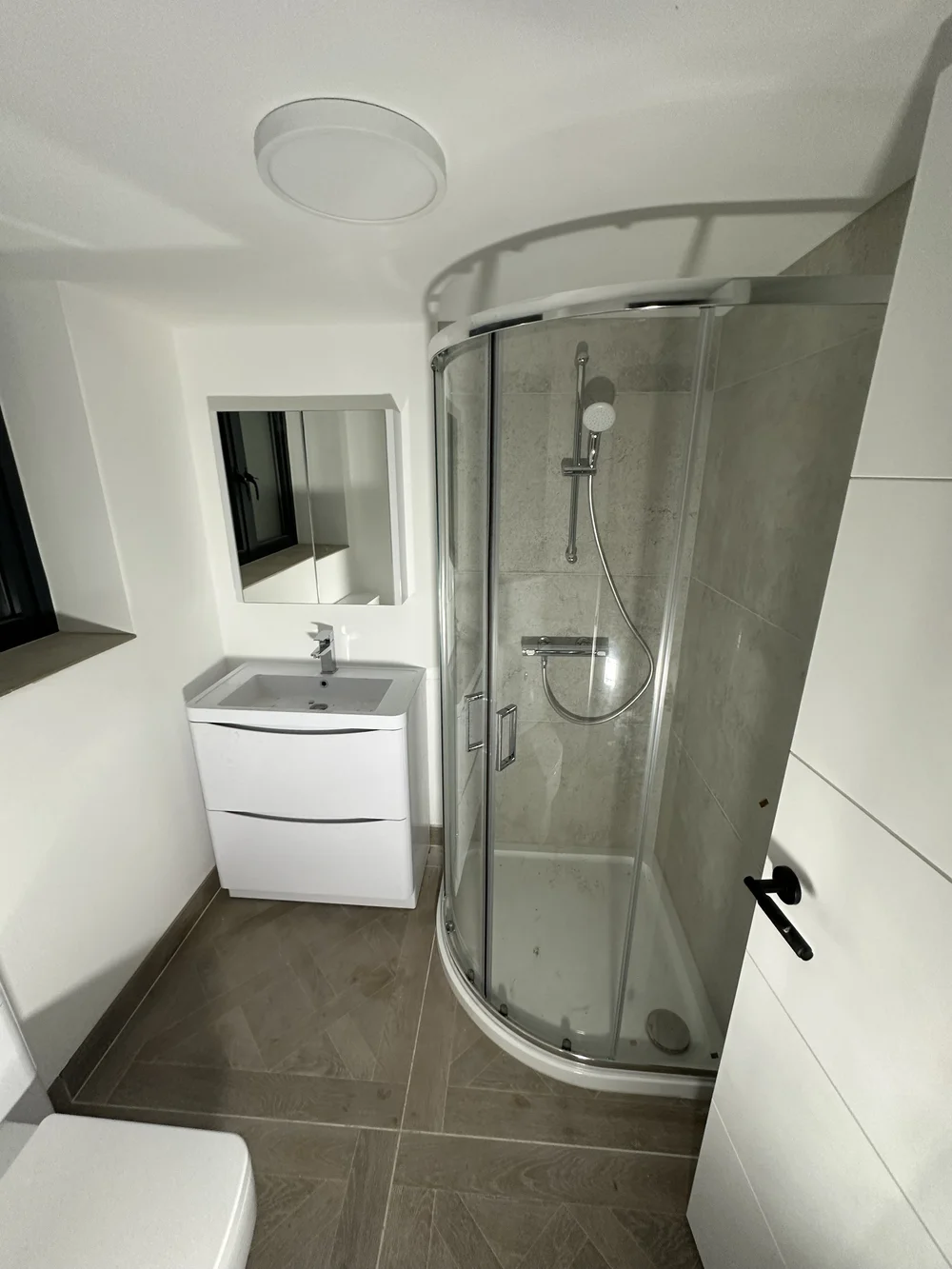 Loft shower room with quadrant enclosure, herringbone tile floor and floor-standing vanity — bathroom installation Haslemere