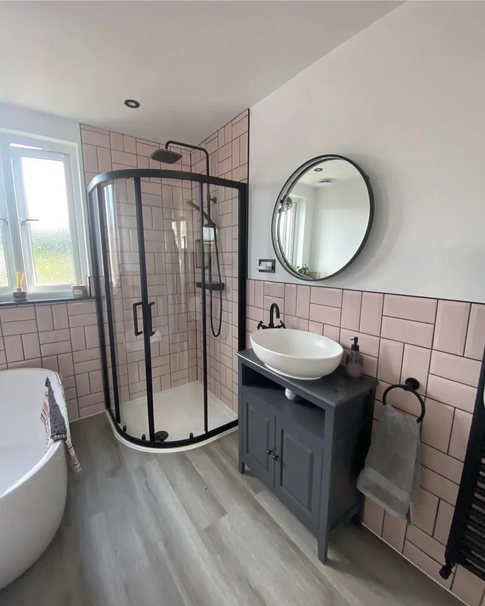 Pink metro-tiled bathroom with black-framed quadrant shower, freestanding bath and vessel basin — bathroom renovation Haslemere