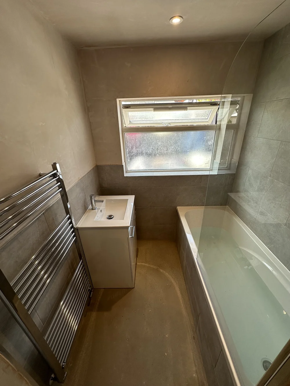 Compact family bathroom mid-renovation with fresh plaster, stone tiling and new bath — bathroom renovation Haslemere