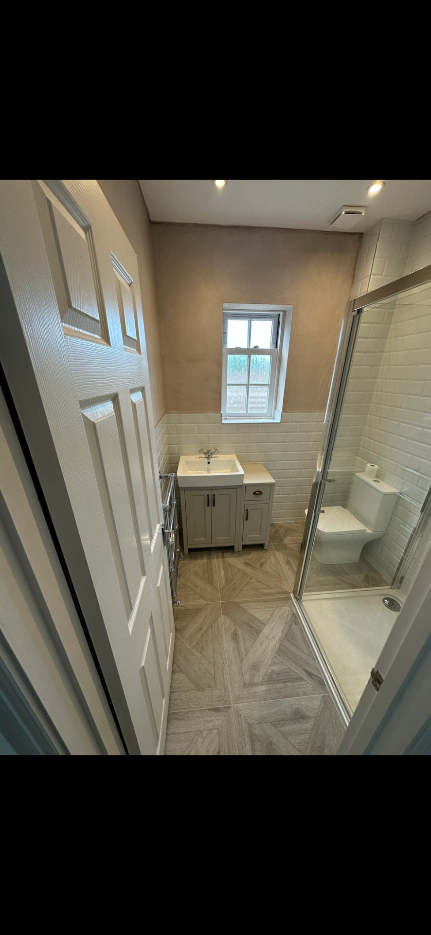 Compact shower room with shaker vanity, beveled metro tiles and chevron parquet floor — bathroom installation Haslemere