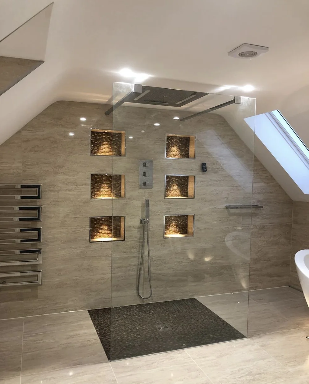 Luxury loft wet room with travertine walls, mosaic niches and frameless glass screen — Haslemere bathroom fitters
