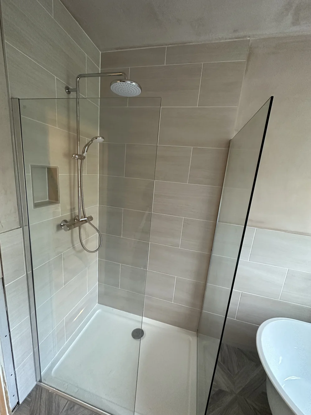 Walk-in shower with cream metro tiles, brushed nickel rainfall column and glass screen — bathroom installation Haslemere